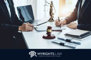 Two people in business attire sit at a desk with legal documents, a gavel, scales of justice, and a laptop; the MYRIGHTS.LAW logo is visible at the bottom, highlighting expert Los Angeles Domestic Violence Lawyer services.