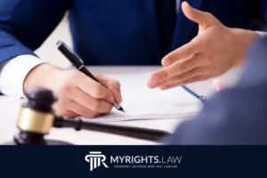 Two people in business attire discuss legal documents at a desk with a gavel, pen, and paper; logo and text 