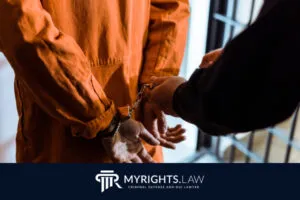A person in an orange prison uniform is being handcuffed by another individual in a jail setting. The image features the MYRIGHTS.LAW logo and text, highlighting the need for a Los Angeles Misdemeanor Lawyer.