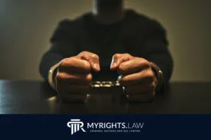 A person sits at a table with wrists in handcuffs, hands clenched, with a logo and text for MyRights.Law, Los Angeles Misdemeanor Lawyer and criminal defense attorney, at the bottom.