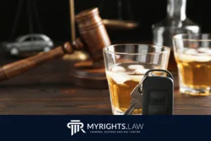 Un vaso de whisky con hielo, las llaves del coche y un mazo descansan sobre una mesa de madera, lo que resalta la importancia de tomar decisiones responsables. La marca MYRIGHTS.LAW en la parte inferior le conecta con un abogado con experiencia en delitos menores de Los Ángeles.