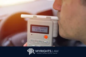 Una persona sopla en un alcoholímetro que muestra un contenido de alcohol de 0,000 mg/L, con un cartel de Abogado de Delitos Menores de Los Ángeles MyRights.Law en la parte inferior.