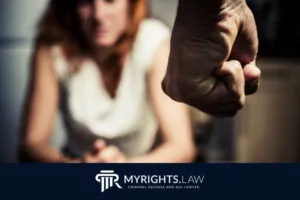 A close-up of a clenched fist in the foreground with a distressed woman sitting in the background; MYRIGHTS.LAW logo and text at the bottom, highlighting the need for a Los Angeles Domestic Violence Lawyer.