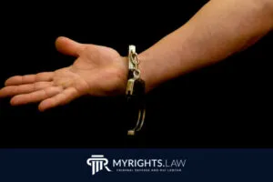 El brazo extendido de una persona con una esposa abierta en la muñeca, sobre un fondo negro, destaca las leyes de violencia doméstica de California. El logotipo y el eslogan de MyRights.Law aparecen en la parte inferior.