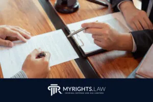Two people in business attire review and sign documents at a wooden desk with a gavel and clipboard, advertising MyRights.Law, Pasadena Criminal Defense Attorney and DUI Lawyers.