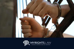 A person’s hands in handcuffs gripping jail bars, symbolizing the need for a skilled Highland criminal defense attorney, with the logo “MYRIGHTS.LAW Criminal Defense and DUI Lawyers” at the bottom.