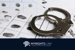 Las esposas descansan sobre hojas de huellas dactilares, con el logotipo de MYRIGHTS.LAW y un texto que indica los servicios de un abogado de defensa penal en Chino en la parte inferior.