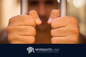 Un hombre agarra los barrotes de una celda con ambas manos; la imagen muestra el logotipo de My Rights Law y el texto 
