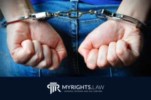 Persona con jeans azules y manos esposadas a la espalda; logotipo y texto “MYRIGHTS.LAW Abogado de Defensa Criminal y DUI” en la parte inferior, prestando servicios en West Covina.