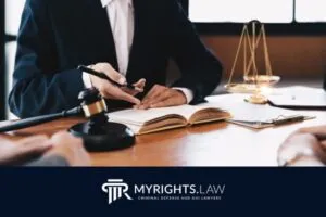 A criminal defense attorney reviews documents at a desk with scales of justice, a gavel, and open book;