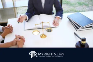 Un abogado de Chino se reúne con un cliente en un escritorio, rodeado de libros legales, un mazo y una balanza de justicia; el logotipo de My Rights Law se muestra en la parte inferior.