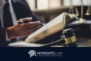A person reads a legal book at a desk with a gavel, scales of justice, and pen—reflecting the focus of a Torrance Criminal Defense Attorney—with the MyRights.Law logo and tagline at the bottom.