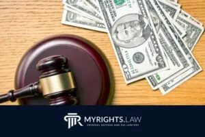 Un mazo de juez y varios billetes de dólares estadounidenses se colocan sobre una superficie de madera encima de un logotipo de MYRIGHTS.LAW, que representa la experiencia de un abogado defensor penal de Fullerton.