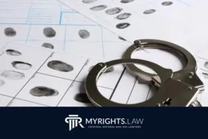 Close-up of handcuffs resting on fingerprint sheets, with a MYRIGHTS.LAW Torrance Criminal Defense attorney logo featured at the bottom of the image.