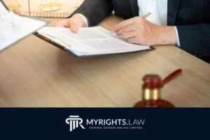 A Garden Grove attorney in a suit reviews legal documents at a desk with a gavel, scales of justice, and the MYRIGHTS.LAW logo—highlighting expertise in criminal defense.