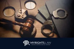 Un mazo de juez, esposas, balanzas legales y libros de leyes sobre un escritorio resaltan la experiencia de un abogado de defensa penal de Ontario, con