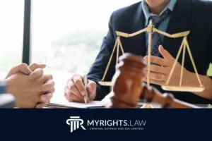 Two people sit at a desk in Temecula with legal documents, a gavel, and a balance scale, discussing their case with an experienced criminal defense attorney as the MYRIGHTS.LAW logo is visible at the bottom.