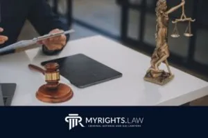 Una persona revisa documentos en un escritorio con un mazo, una tableta y una estatua de la Dama de la Justicia, lo que refleja la diligencia de un abogado defensor penal de Lancaster; 