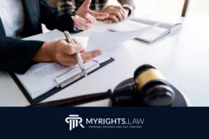 Dos personas revisan documentos legales en un escritorio en Rancho Cucamonga, con un mazo y cuadernos; se muestran el logotipo y el lema de MYRIGHTS.LAW, destacando su experiencia como cómplices de abogados.