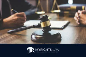 A wooden gavel rests on a desk between two people in suits, with documents and books in the background. The MyRights.Law logo is visible at the bottom, highlighting the expertise of a Rancho Cucamonga Bribery Lawyer.