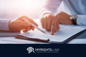Two people review legal documents at a desk with a pen and notepad, alongside the MYRIGHTS.LAW logo and tagline for criminal defense, DUI lawyers, and Rancho Cucamonga Bribery Lawyer services.