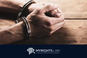 A person in handcuffs sits at a wooden table with their hands clasped. The MyRights.Law logo and tagline for criminal defense, DUI lawyers, and Rancho Cucamonga CACI Removal Lawyer are included.
