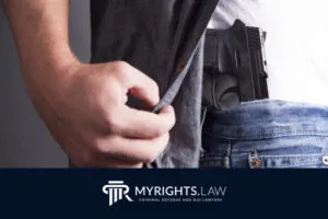 Person lifts shirt to reveal a handgun tucked into the waistband of jeans; MYRIGHTS.LAW criminal defense and DUI lawyers logo, featuring Rancho Cucamonga CACI Removal Lawyer, displayed at the bottom.