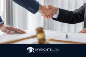 Dos personas vestidas con trajes de negocios se dan la mano sobre un escritorio con documentos legales y un mazo, destacando MyRights.Law, su abogado de confianza de Rancho Cucamonga para delitos relacionados con el alcohol.